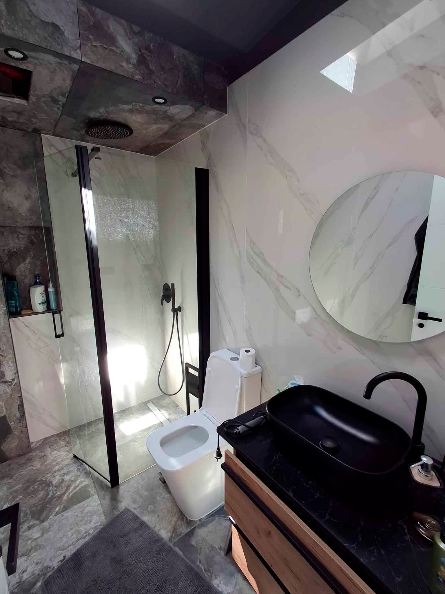Un baño con inodoro, lavabo, espejo y ducha.