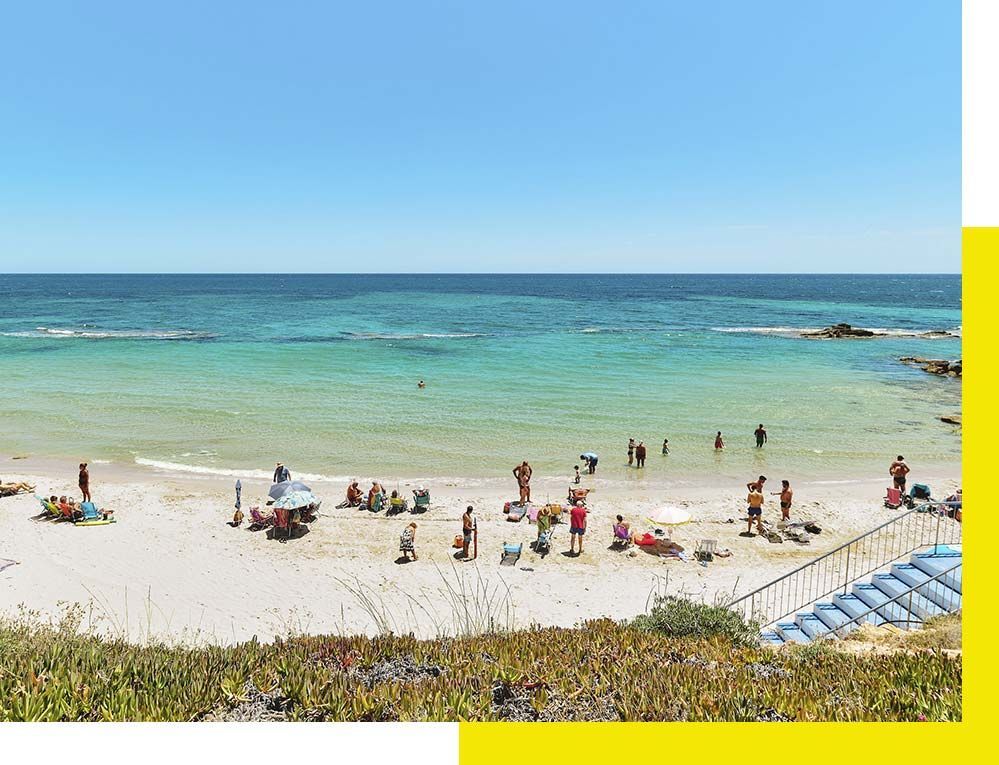 Una camioneta blanca está estacionada frente a un avión que vuela en el cielo.