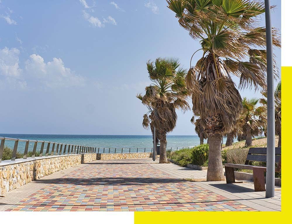 Una camioneta blanca está estacionada frente a un avión que vuela en el cielo.