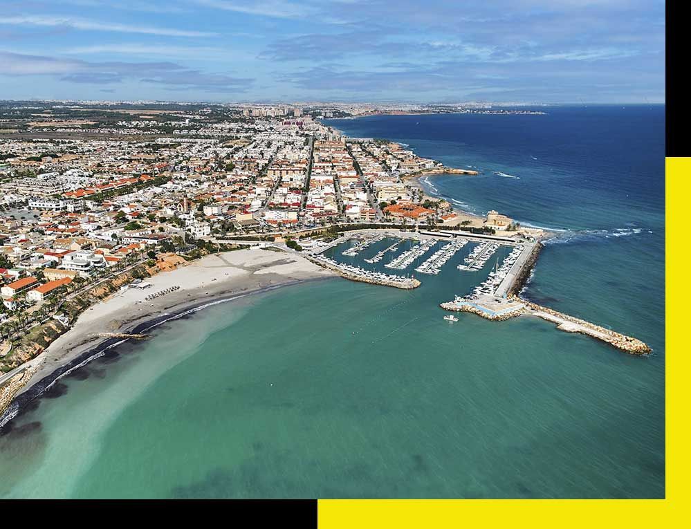 Un hombre con traje y corbata está de pie junto a un coche blanco.