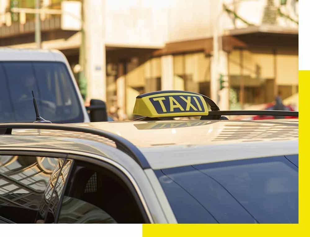 Una camioneta blanca está estacionada frente a un avión que vuela en el cielo.