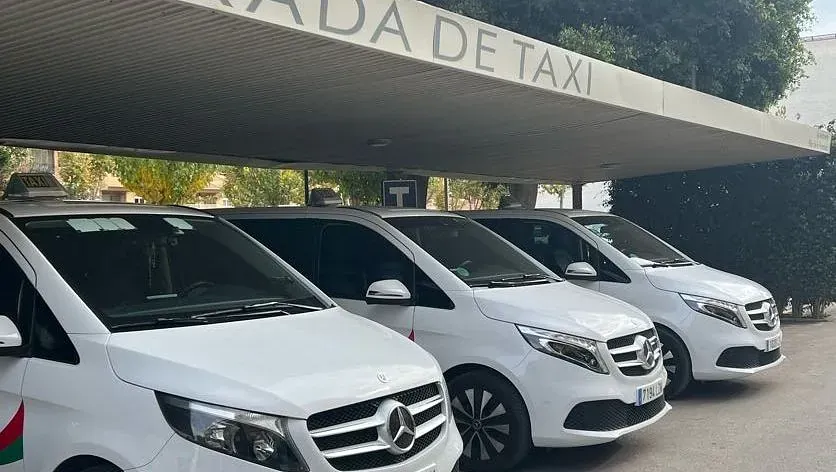 Una fila de furgonetas blancas están estacionadas frente a un edificio.