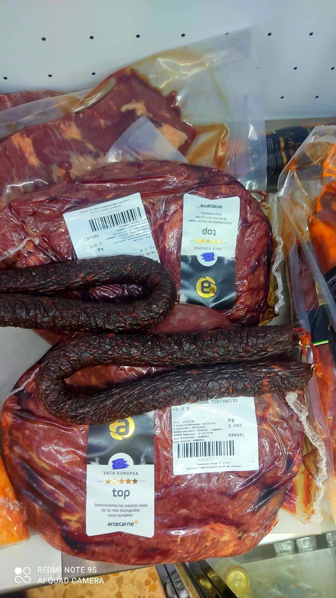 Dos bolsas de carne y salchichas están colocadas una encima de la otra sobre una mesa.