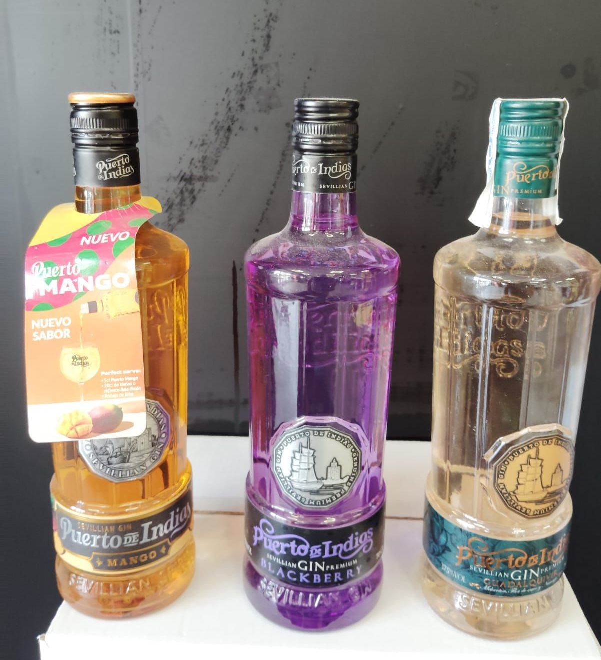 Hay tres botellas de alcohol sobre una mesa, incluida una que dice mango.