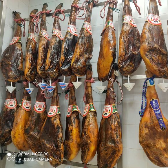 Un montón de jamones están colgados en un estante