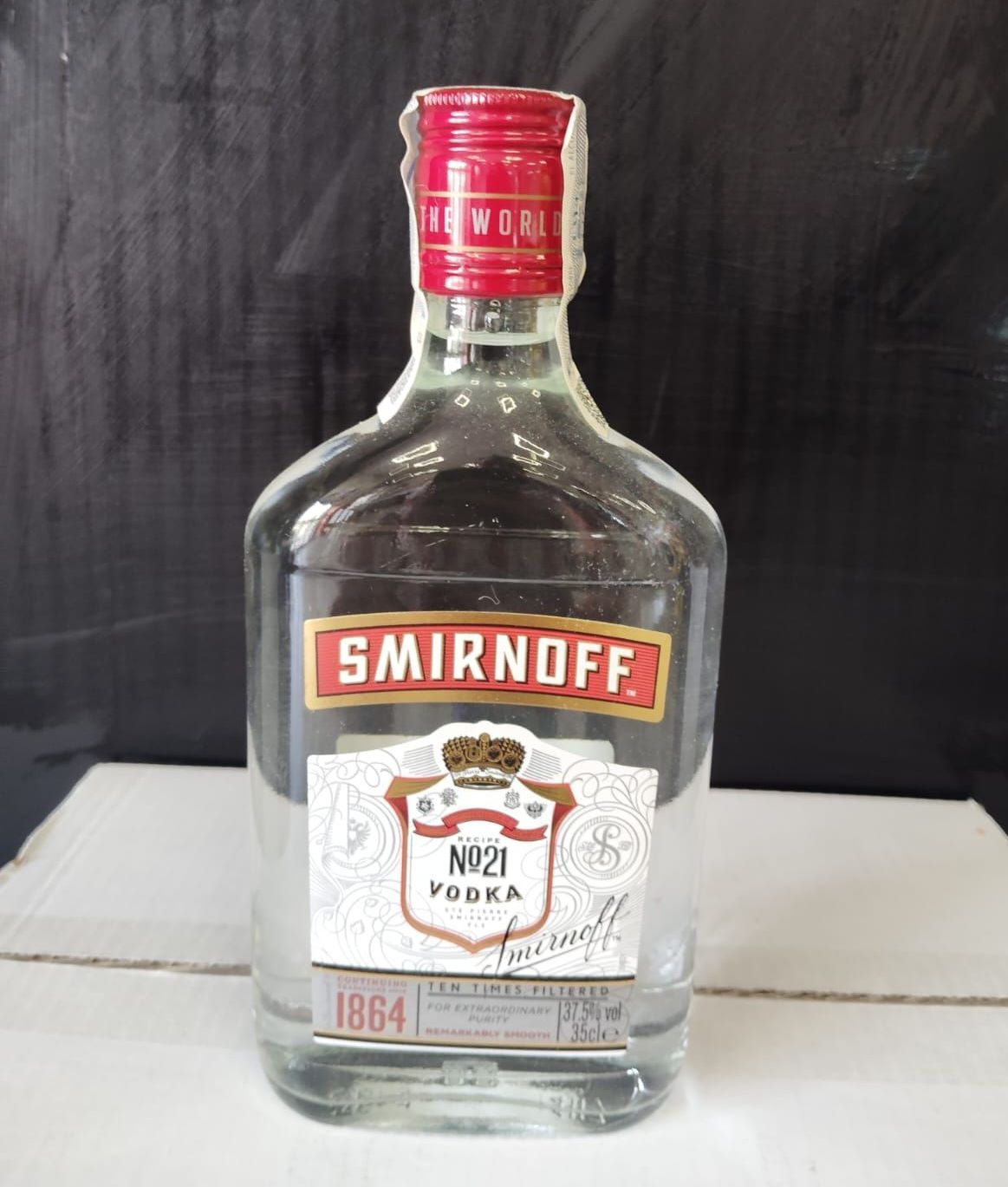 Una botella de vodka Smirnoff con tapón rojo