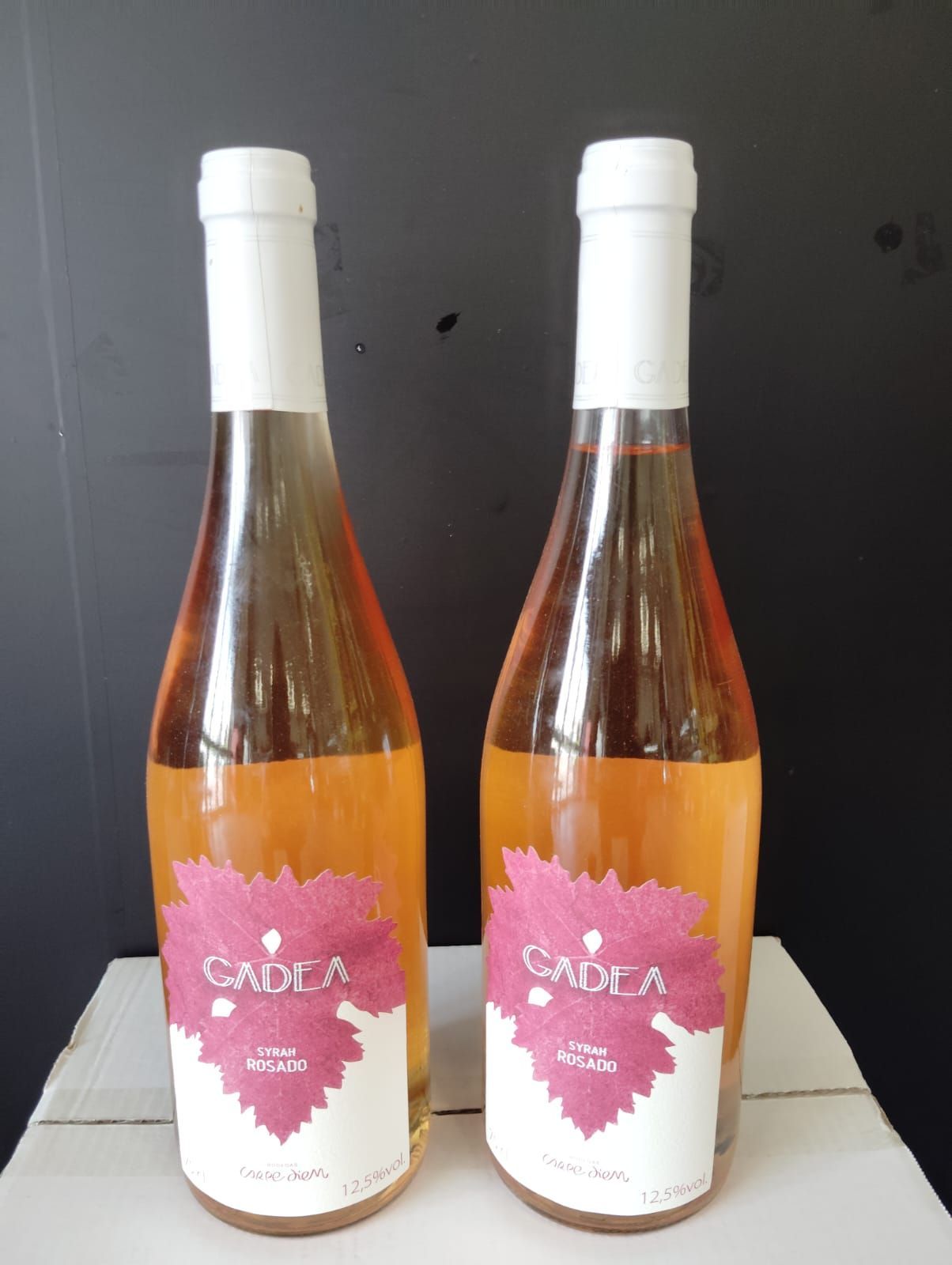 Dos botellas de vino sadila están sobre una caja.