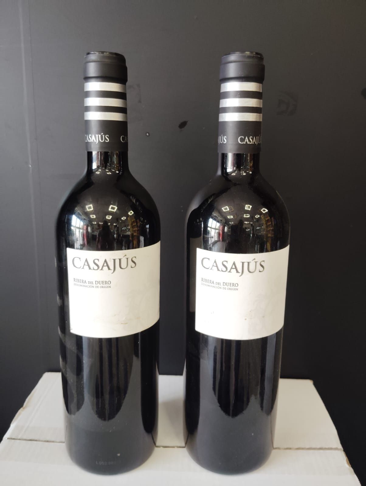 Dos botellas de vino casajus están sobre una mesa.