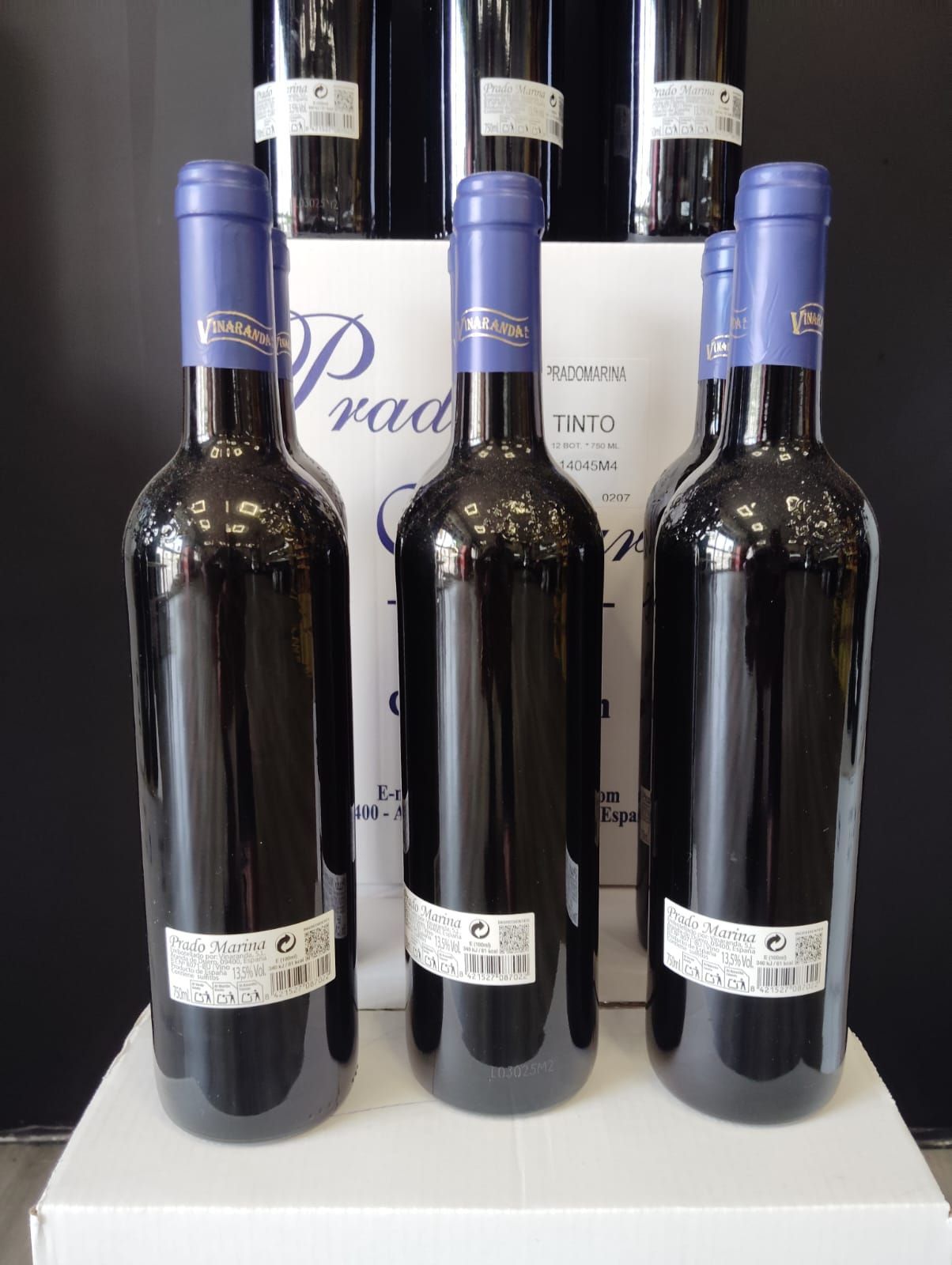 Tres botellas de vino están encima de una caja blanca.