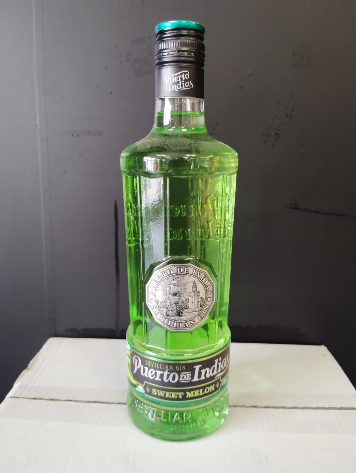 Una botella de líquido verde está encima de una mesa de madera.
