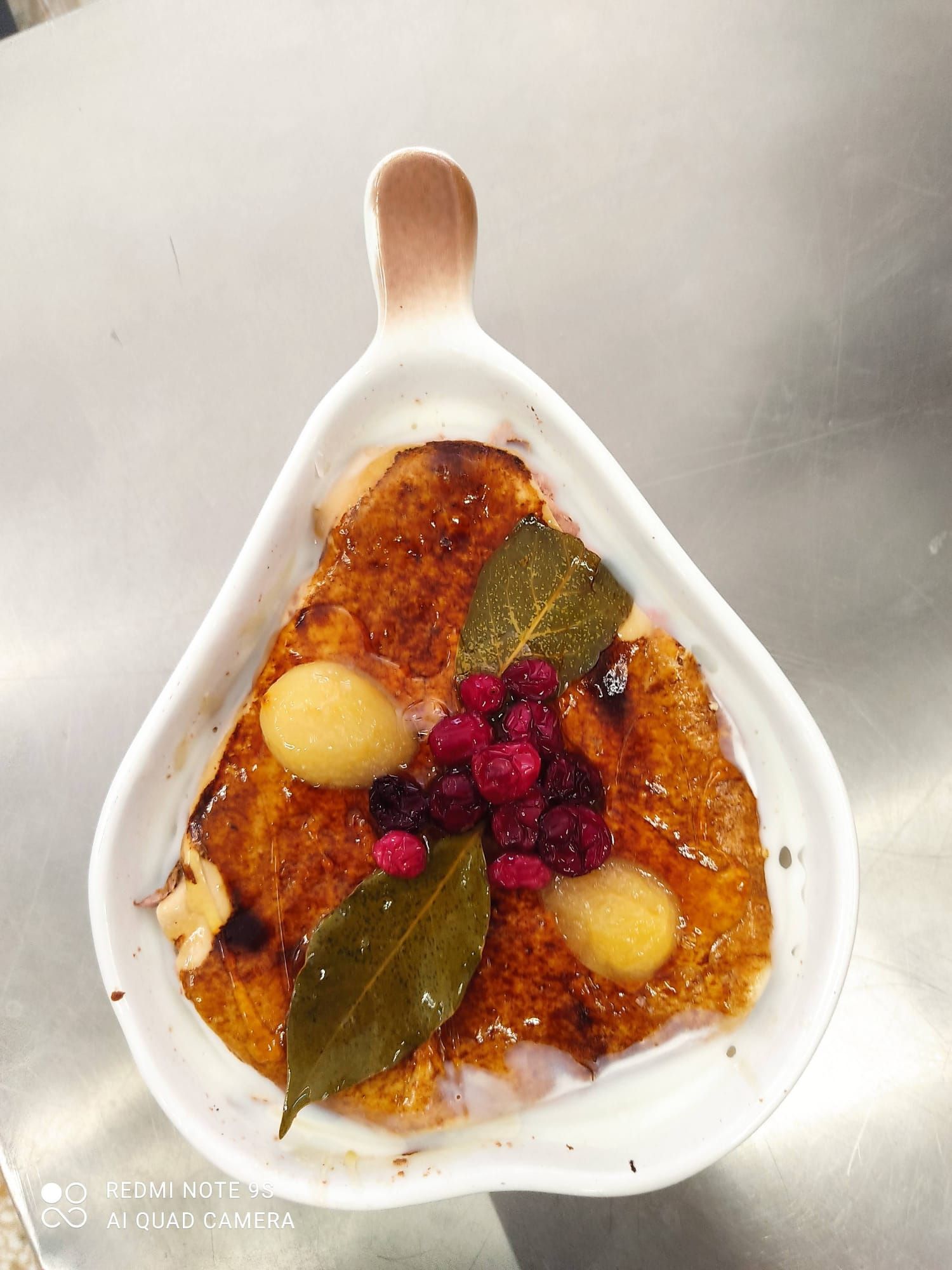 Un recipiente blanco lleno de comida y bayas sobre una mesa.