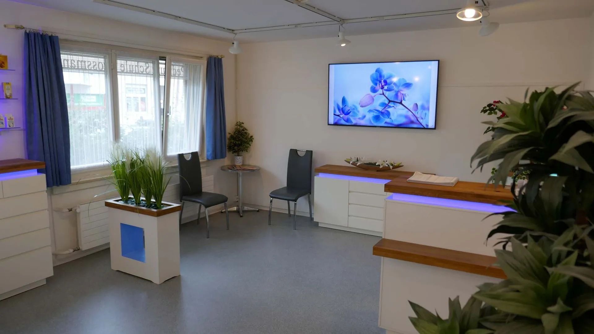 Ein Wartezimmer mit einem grossen Flachbildfernseher an der Wand.