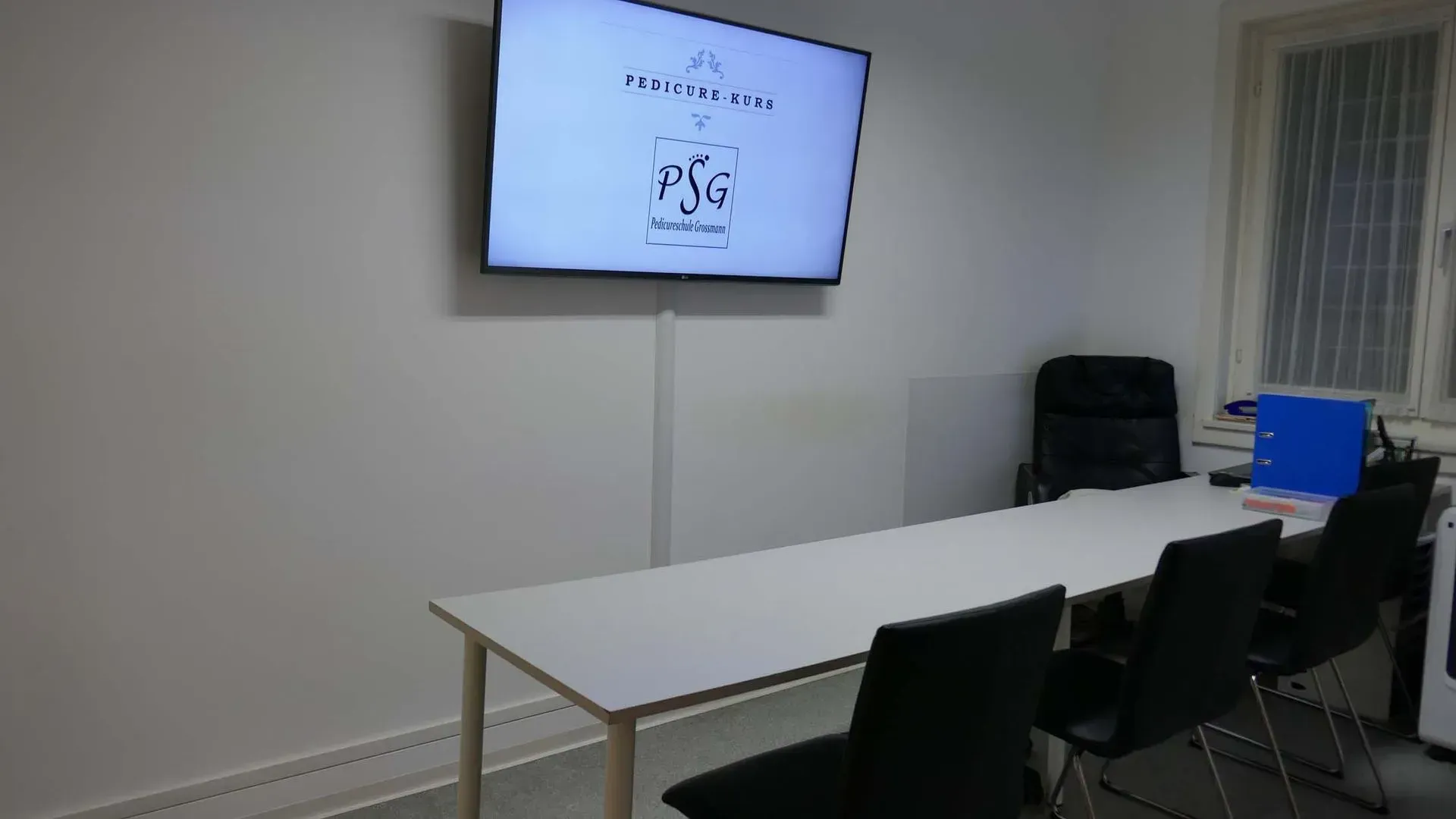 Ein Konferenzraum mit einem langen Tisch und Stühlen und einem Flachbildfernseher an der Wand.