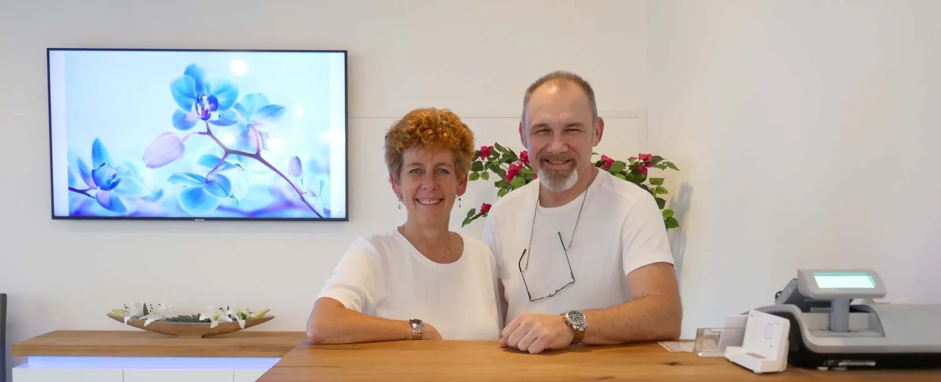 Ein Mann und eine Frau sitzen an einer Theke vor einem Fernseher.