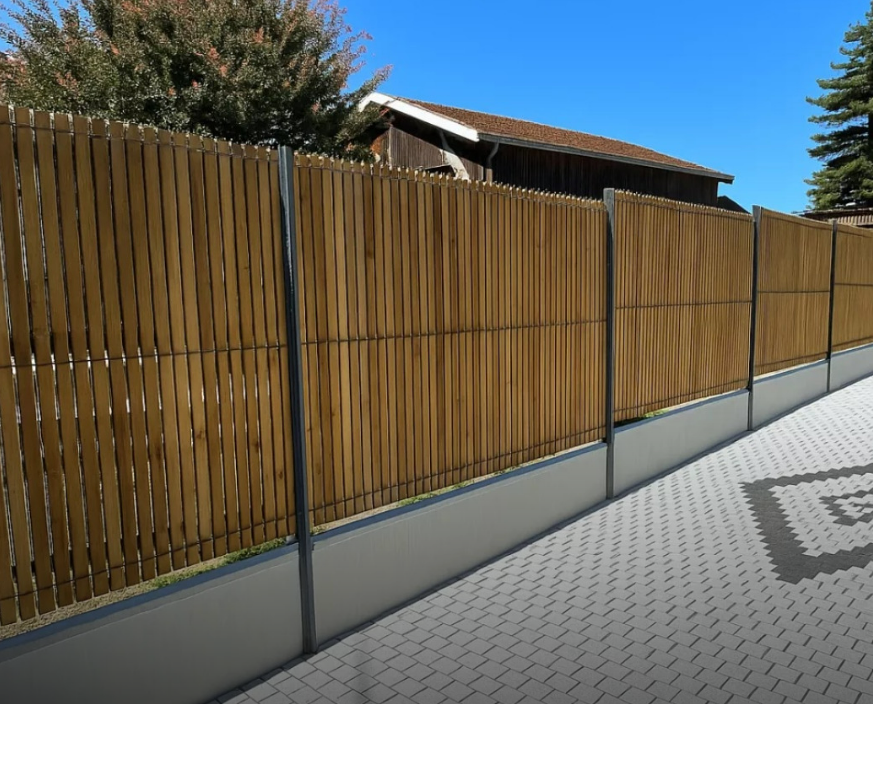 Clôture en bois avec poteaux en métal gris le long d'une terrasse pavée sous un ciel bleu
