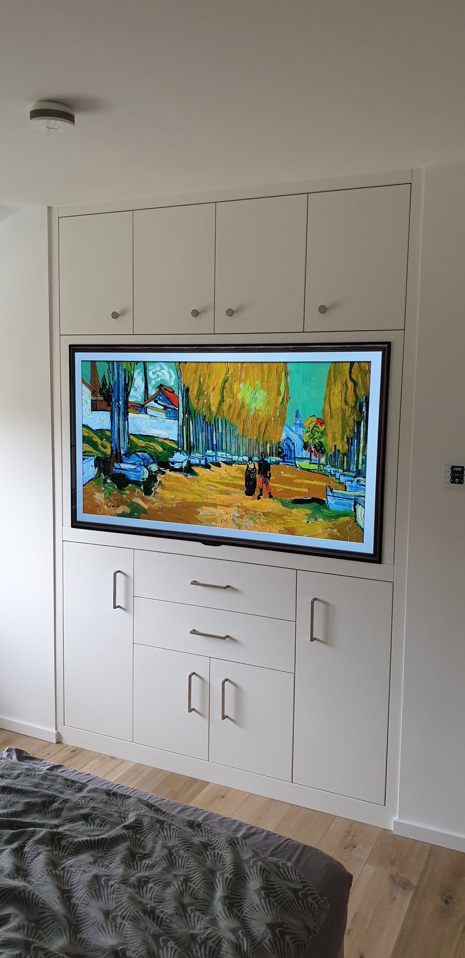 Ein Schlafzimmer mit einem Flachbildfernseher, der an der Wand über einem Bett hängt.