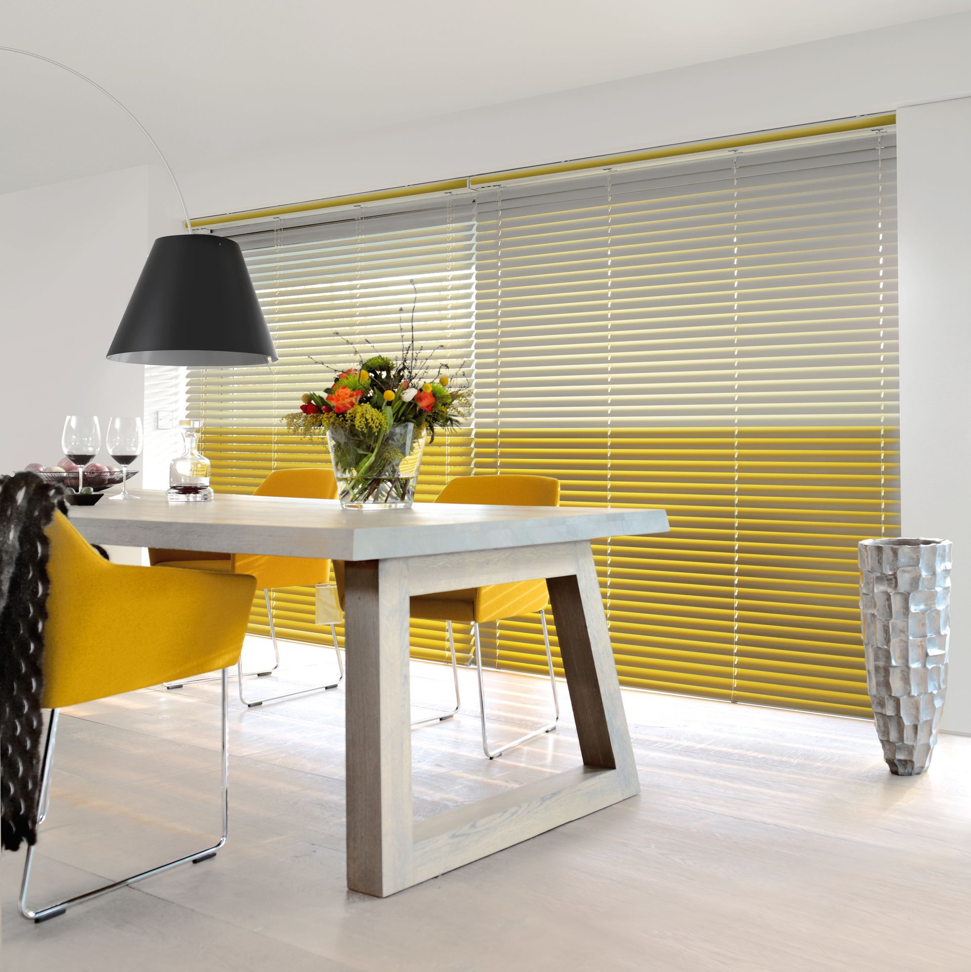 Ein Esszimmer mit gelben Stühlen und einem Tisch mit einer Blumenvase darauf
