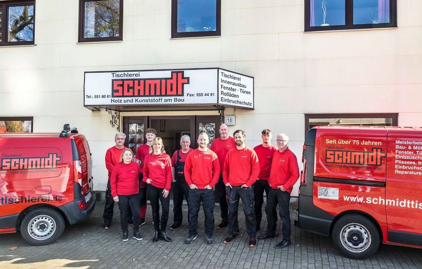 Eine Gruppe von Menschen steht vor einem Gebäude mit einem Schild mit der Aufschrift „Schmidt“