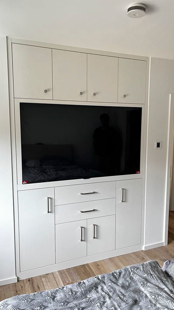 Ein Wohnzimmer mit einem in die Wand eingebauten Flachbildfernseher.