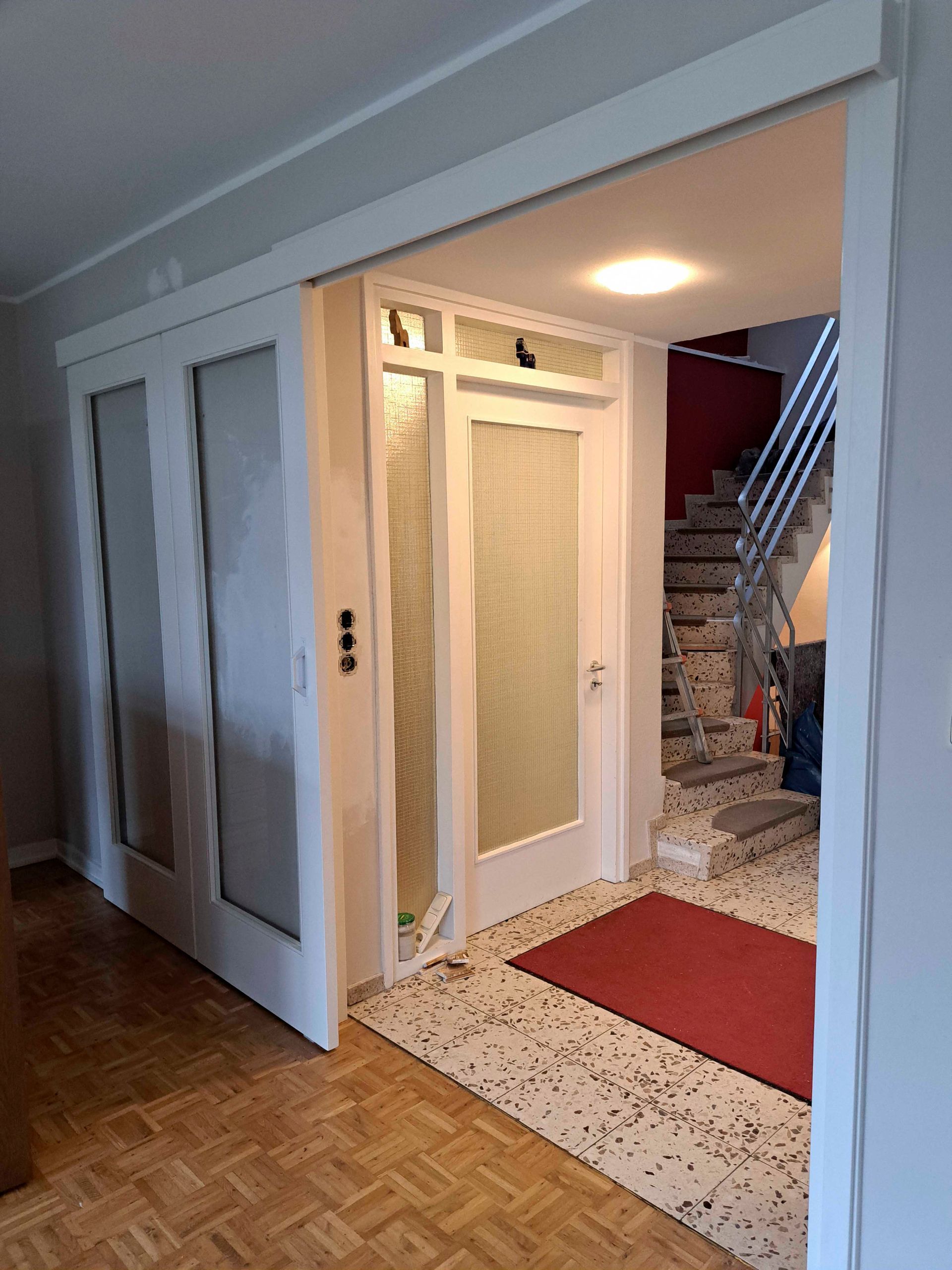 Ein Raum mit einer Treppe und einer Glasschiebetür