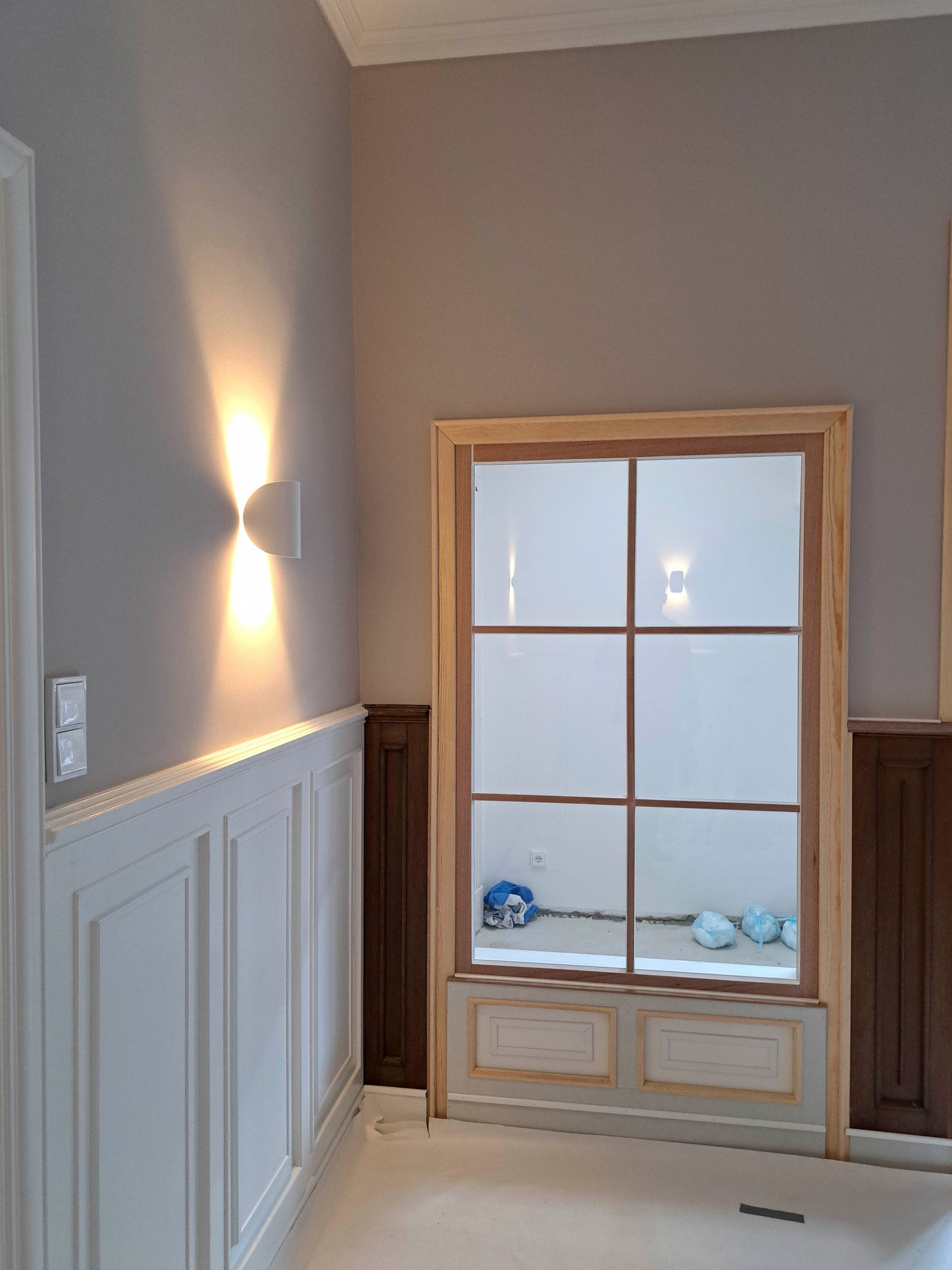 Ein Flur mit einem Fenster und einer Lampe an der Wand