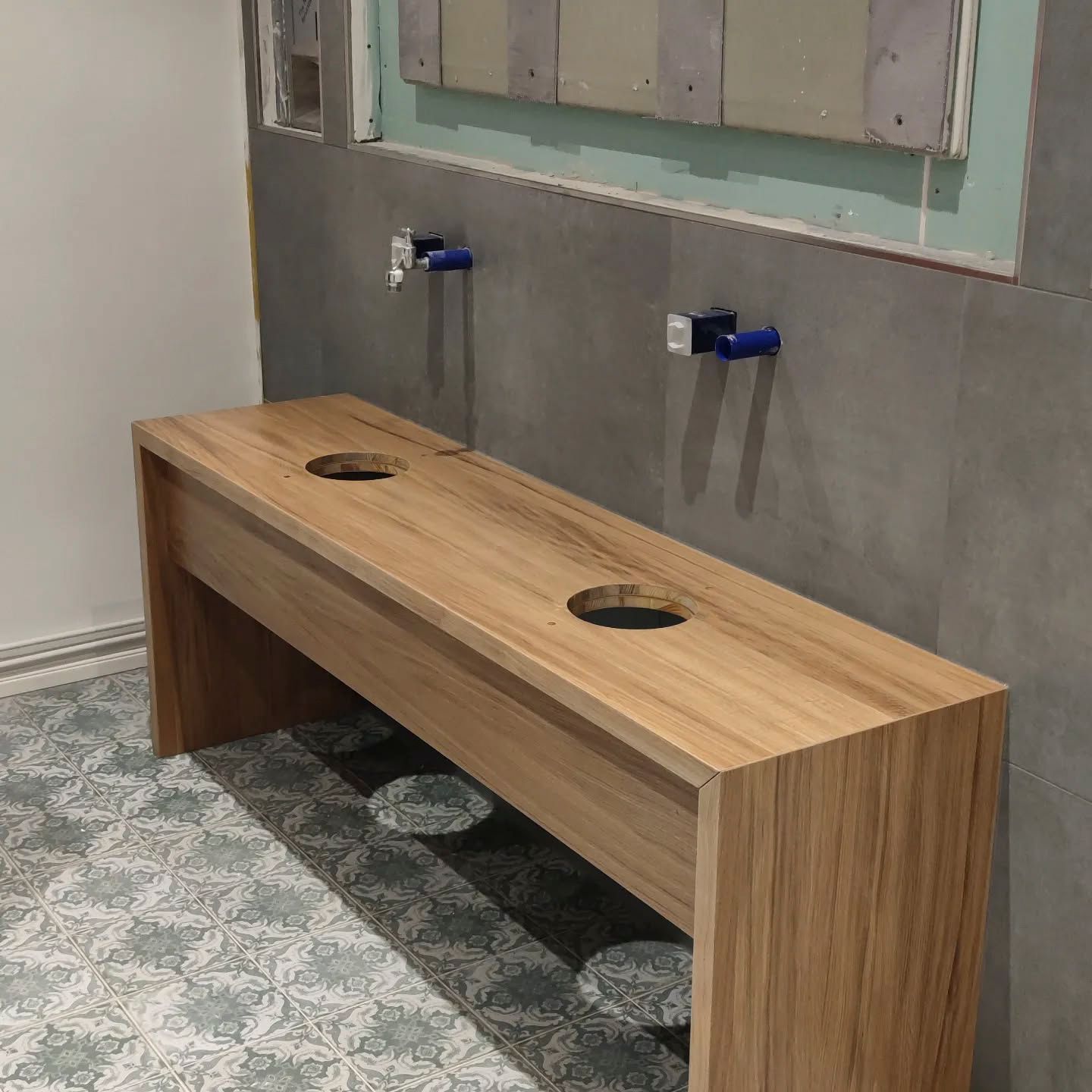 Eine Holzbank mit zwei Löchern darin in einem Badezimmer