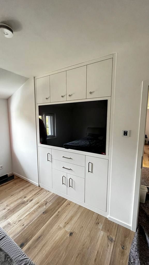 Ein Wohnzimmer mit Hartholzböden und einem an der Wand montierten Flachbildfernseher.