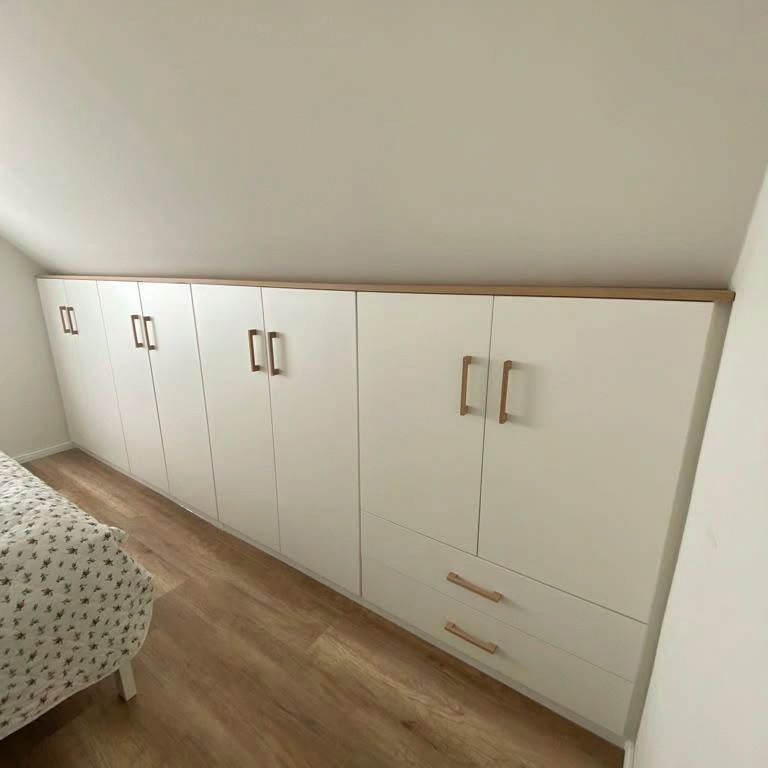 Ein Schlafzimmer mit weißen Schränken und Schubladen und einem Bett.