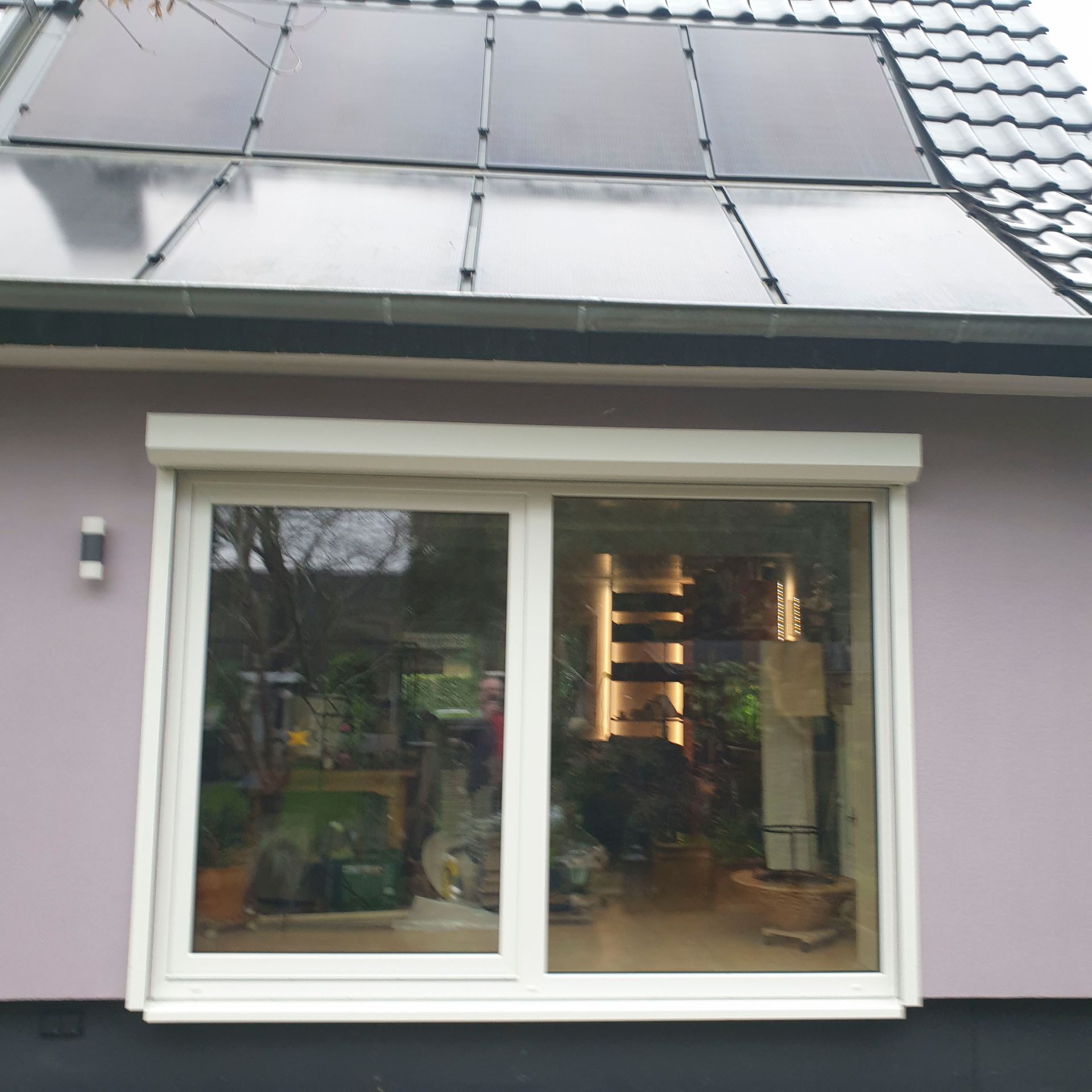 Ein Haus mit einer Glasschiebetür und Solarzellen auf dem Dach