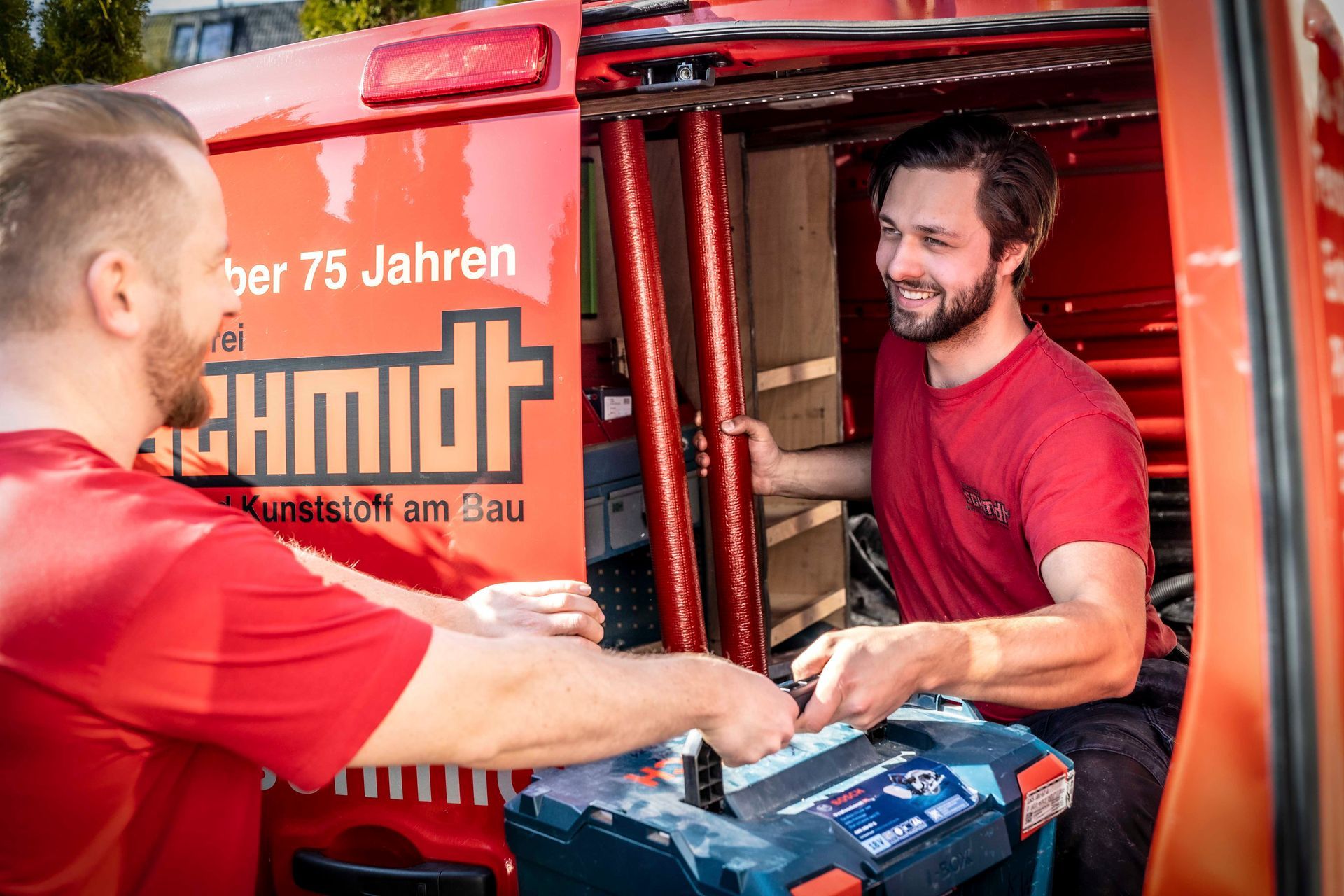 Zwei Männer arbeiten in einem roten Lieferwagen.