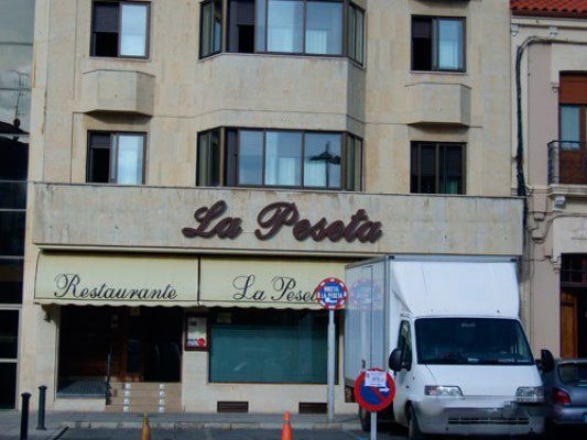 Un camión blanco está estacionado frente a un restaurante llamado La Peseta.