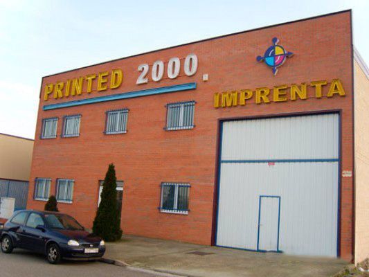 Un coche está aparcado delante de un edificio que dice Imprenta 2000