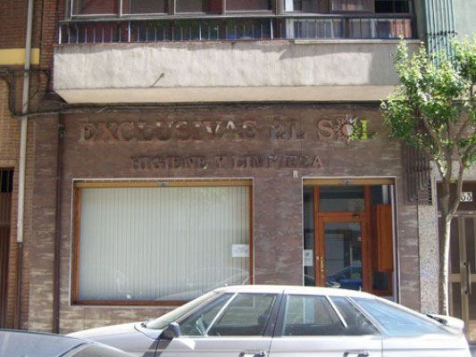 Un coche está aparcado delante de un edificio que dice excusas el sol