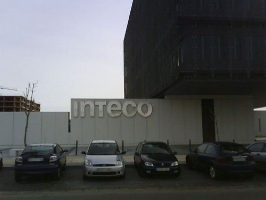 Los coches están aparcados delante de un edificio que dice inteco