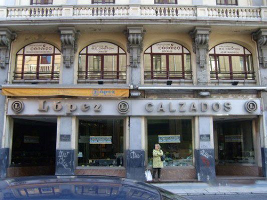 Una mujer está parada frente a una tienda llamada López Calzados.