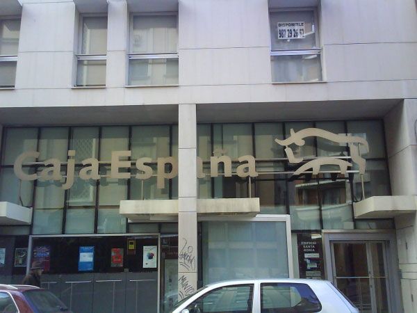 Un coche blanco está aparcado delante de un edificio que dice caja espna