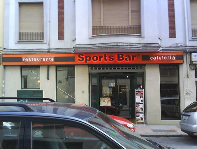 Un bar deportivo con coches aparcados delante.