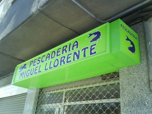A green sign that says pescaderia miguel llorete