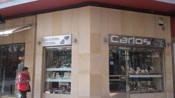 Una mujer está parada frente a una tienda llamada Carlos.