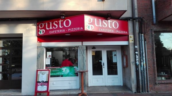 Un restaurante con un cartel rojo que dice gusto