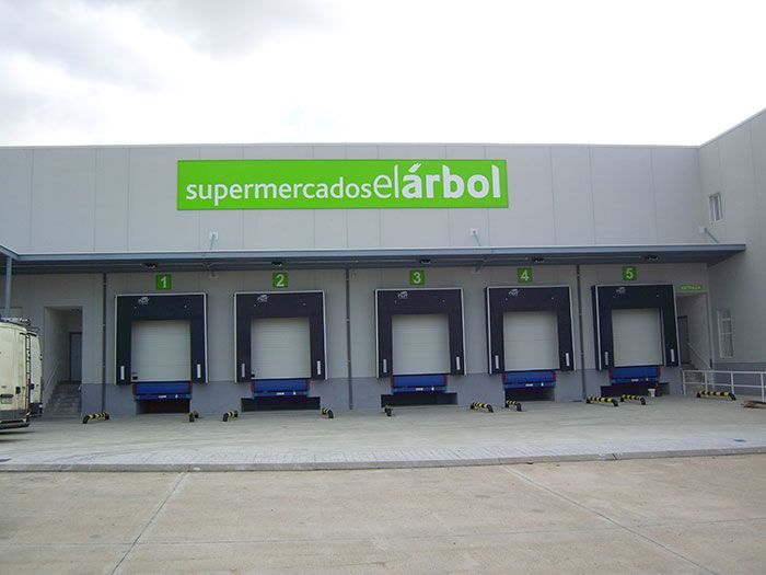 Un edificio con un cartel verde que dice supermercados el arbol