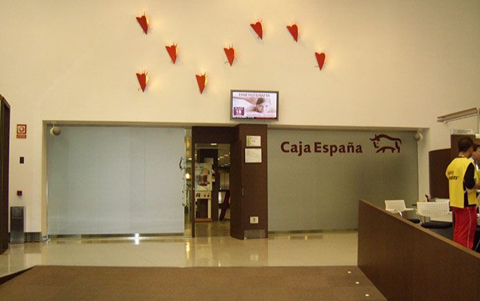 Un hombre con una chaqueta amarilla se encuentra frente a la Caja España.