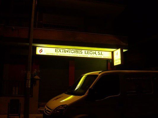 Una furgoneta amarilla está aparcada delante de un edificio con un cartel que dice extintores lideres sl