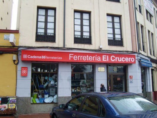 Un coche azul está estacionado frente a una tienda llamada ferretería el crucero.
