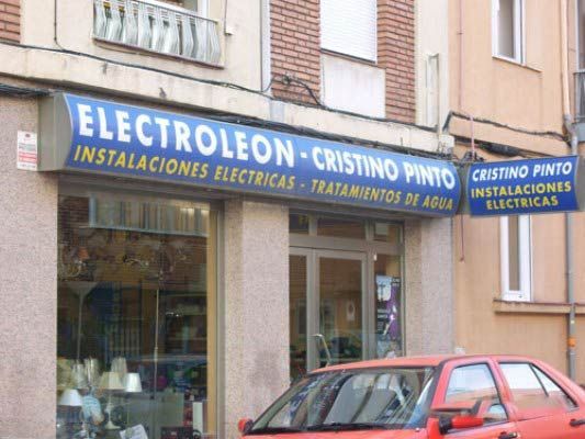 Un coche rojo está aparcado delante de una tienda llamada electroleon