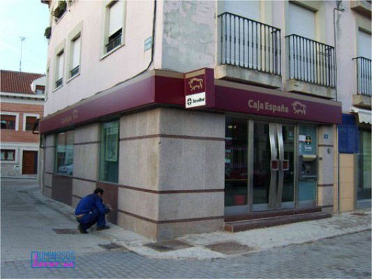 Un hombre arrodillado frente a un edificio de la Caja Española.