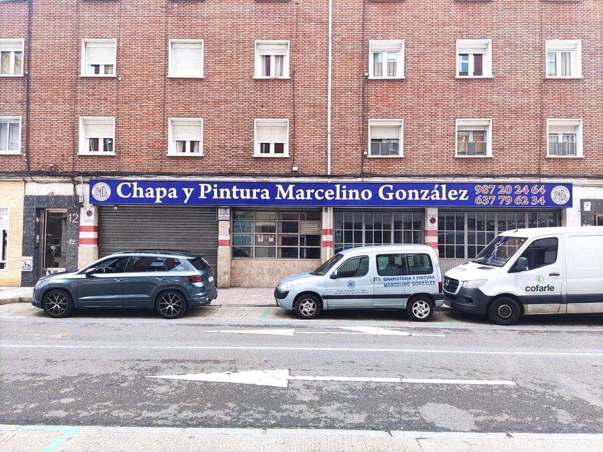 Una fila de coches están aparcados delante de un edificio.