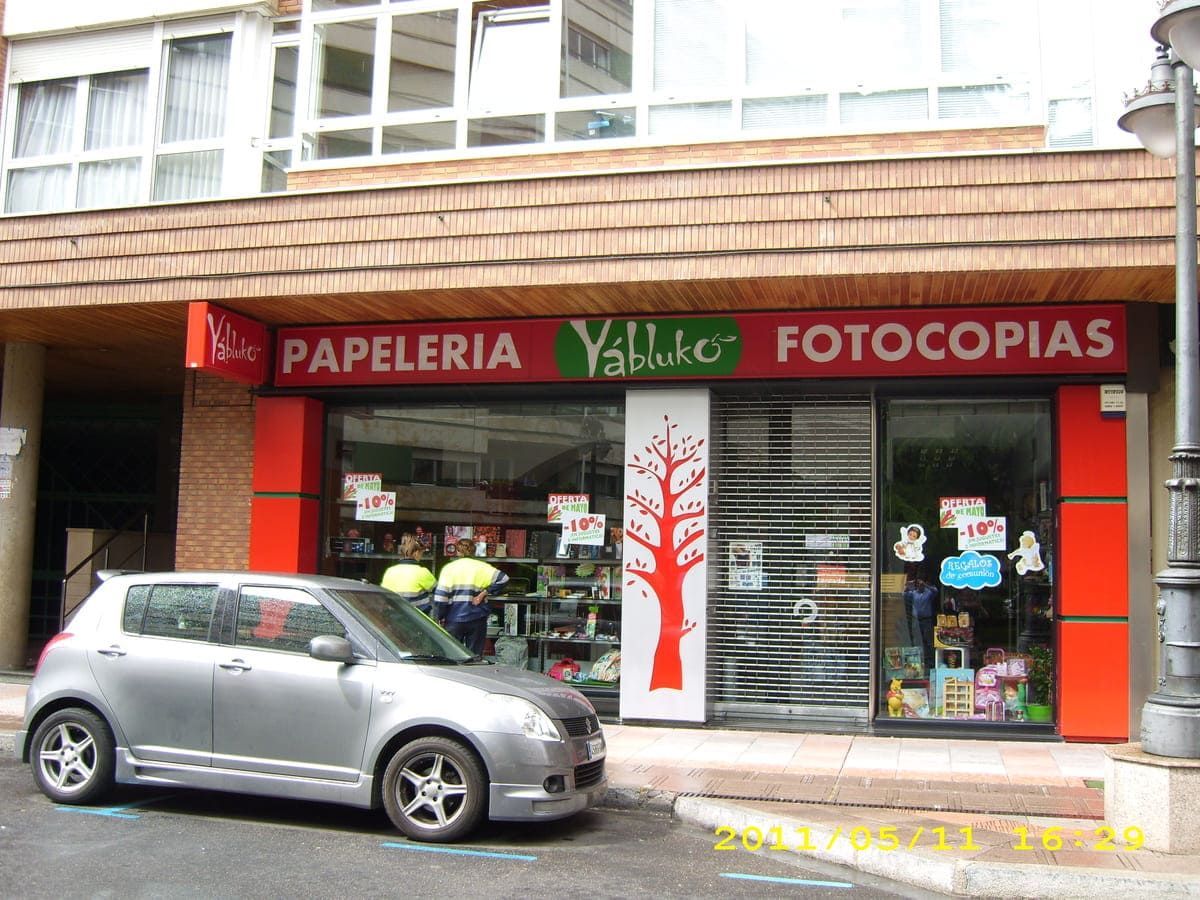 Un coche está aparcado delante de una tienda llamada papeleria