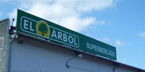 Un cartel verde en el costado de un edificio dice El Arbol Supermercado