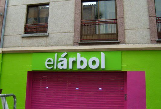 Un edificio verde y rosa con un cartel que dice elarbol